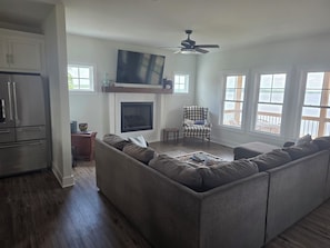 A living room with a sectional sofa, a fireplace, a television, and a ceiling fan.