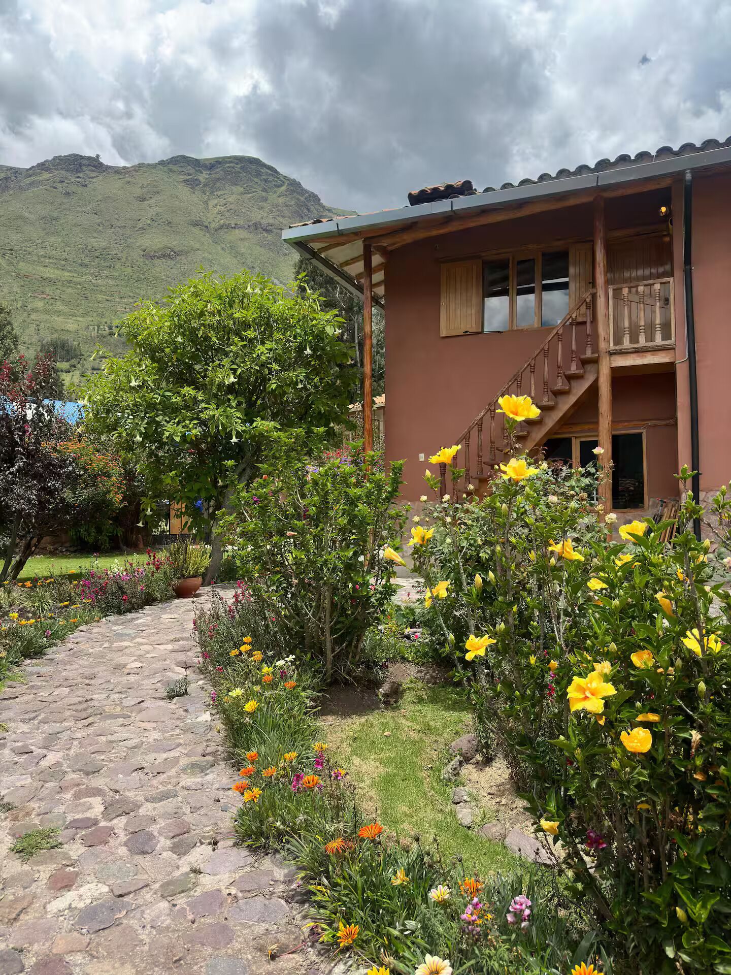 A two-story building with a stone pathway leading to the entrance, surrounded by a variety of colorful flowers and greenery.