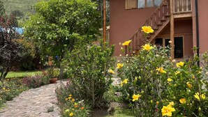 Un edificio su due piani con un vialetto in pietra che conduce all'ingresso, circondato da fiori colorati e vegetazione.