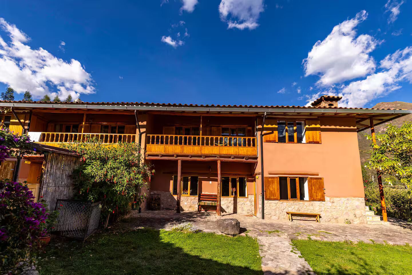 Ein zweistöckiges Gebäude mit Balkon, Steinmauern und einem Garten.