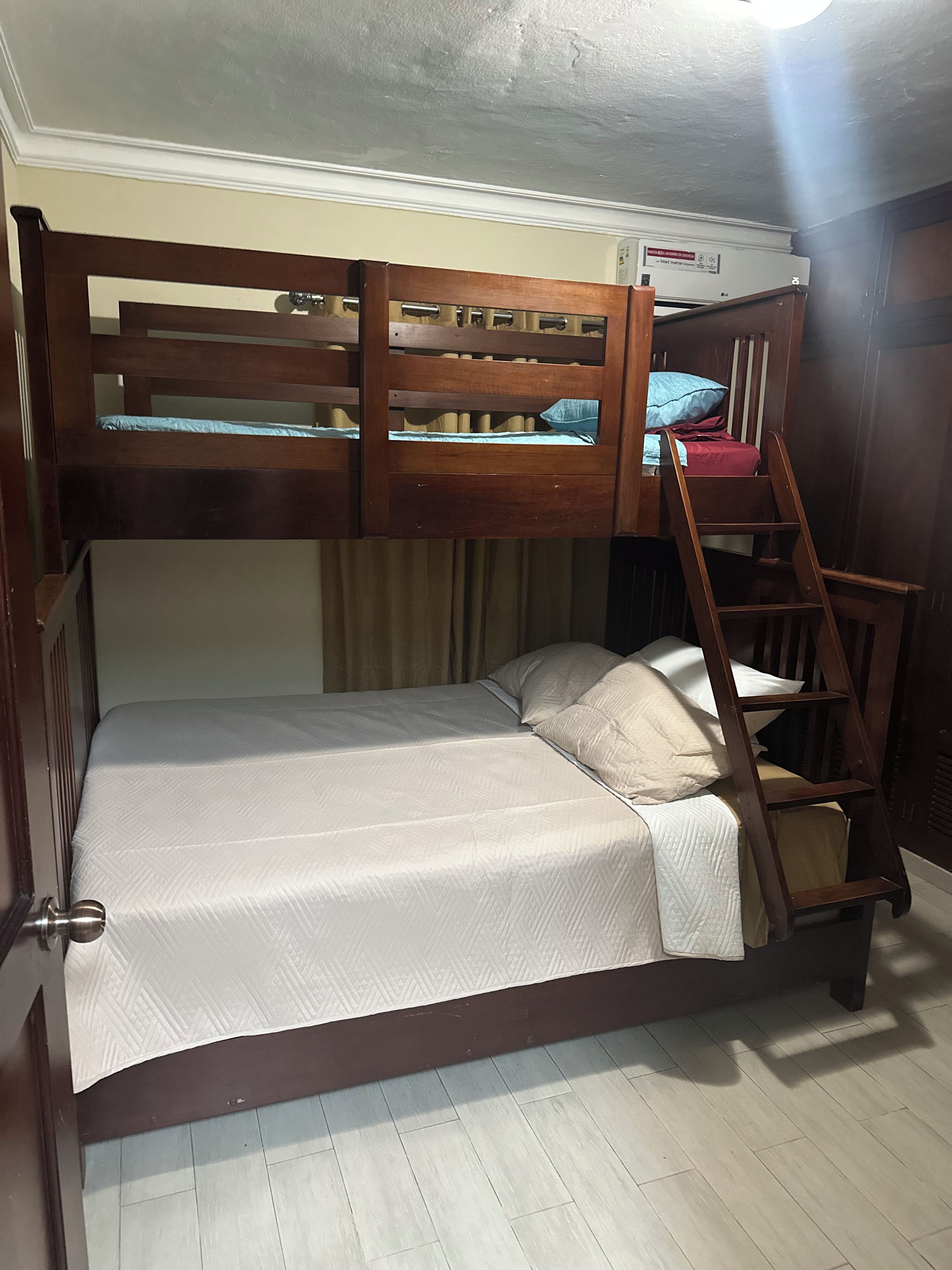 Una cama litera con escalera, una cama individual abajo y un ventilador de techo.