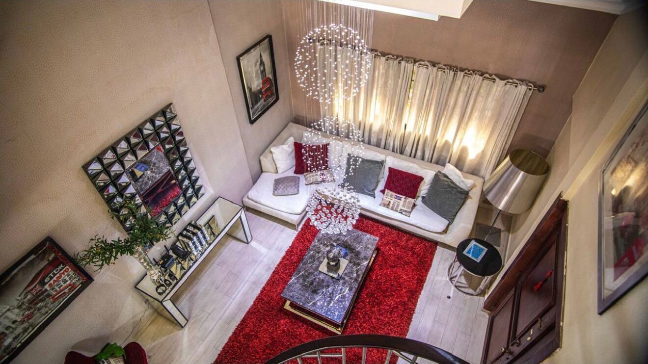 Un salon avec un canapé, un tapis rouge et un luminaire décoratif.