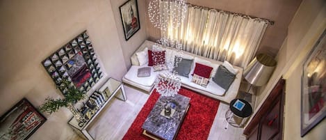 Een woonkamer met een bank, een rood vloerkleed en een decoratieve lamp.