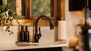 Eine Küche mit einem modernen Wasserhahn, einem Holzfensterrahmen und einer weißen Fliesenwand.