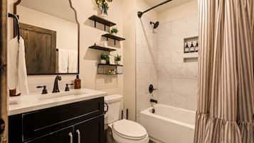 A bathroom with a white sink, black cabinets, a toilet, a bathtub, and a shower curtain.