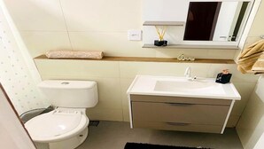 A compact bathroom with a toilet, a sink with a mirror above, and a shelf with toiletries. - Apartment near Maracanã Stadium, Rio de Janeiro, Brazil (Rio de Janeiro)