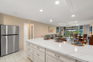 A modern kitchen with a large island, stainless steel refrigerator, and a dining area with a view. - Relaxing 1BD Condo with Partial Ocean Views in Kaanapali - Eldorado F202 (Lahaina)