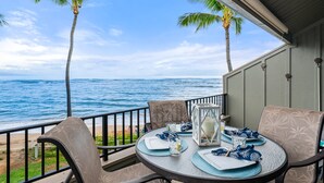 A table set for two with a view of the ocean and palm trees. - Spacious Oceanfront Condo in West Maui - Kahana Village 4 (Lahaina)