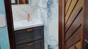 Ein Badezimmer mit Marmorwand, Holztür und Spiegel.