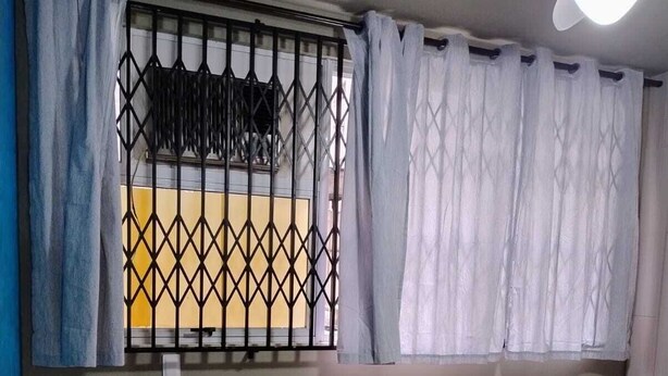 Ein Schlafzimmer mit Bett, Deckenventilator, Fenster mit Vorhängen und Fliesenboden.