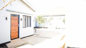 A modern building with a wooden door, a window with bars, and a bicycle parked outside. - Casa de la 2-bedroom townhome in charming Lilongwe neighborhood (Lilongwe)