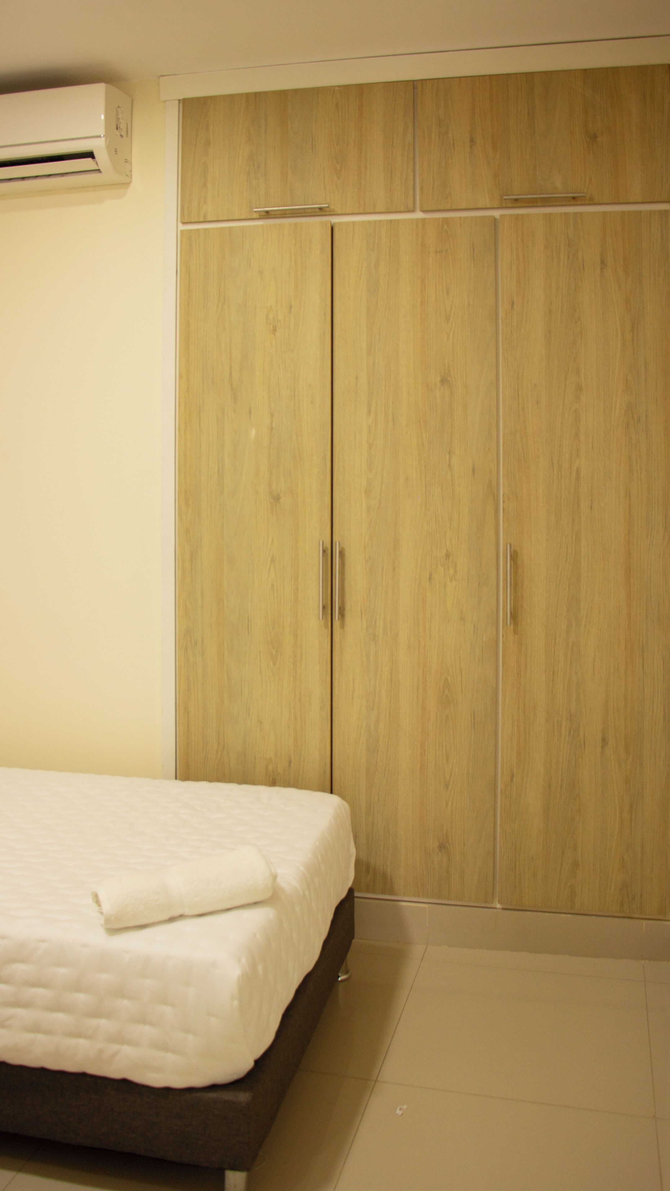 Une chambre à coucher avec un lit, une armoire en bois et un appareil de climatisation.