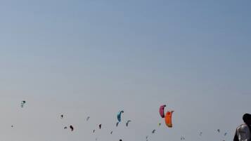 Ein Strand mit Menschen und bunten Drachen am Himmel.