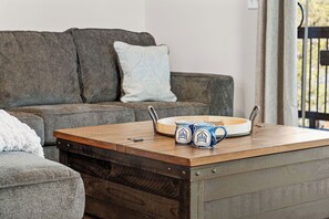 A living room with a wooden coffee table, a sofa, and a window with a view. - Private Hot Tub at The Bobber Stop, Arcade, Community Pools Nearby & Free Attraction Tickets (Hollister)