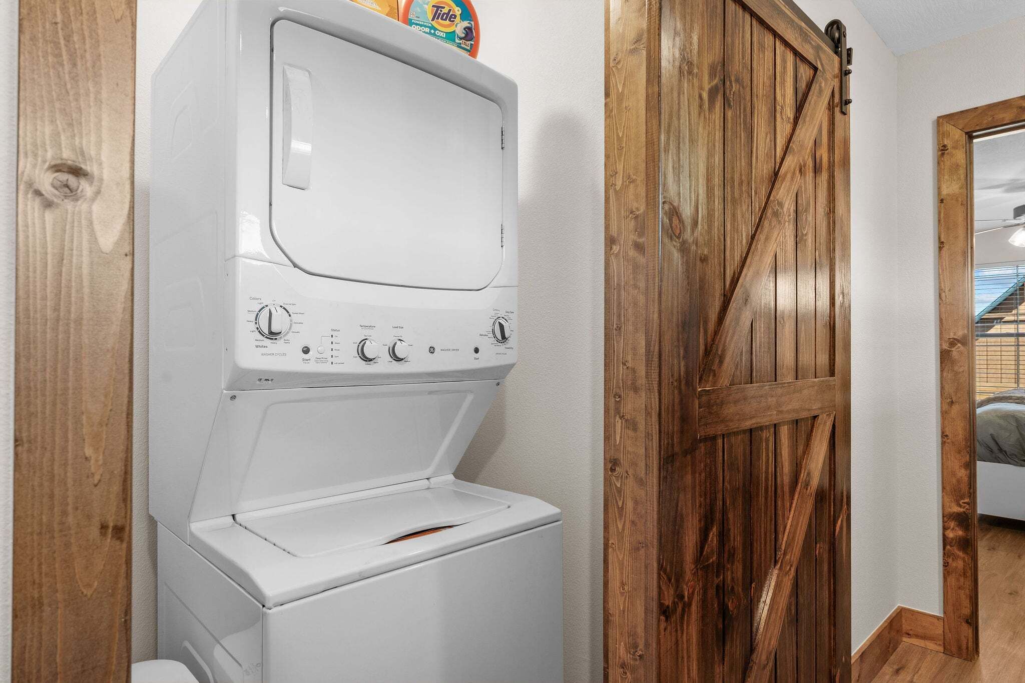 A front-loading washing machine in a room with wooden walls and a barn-style door.