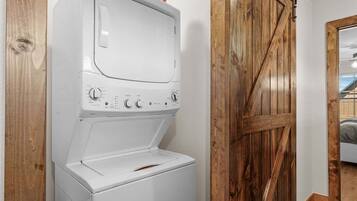 A front-loading washing machine in a room with wooden walls and a barn-style door.