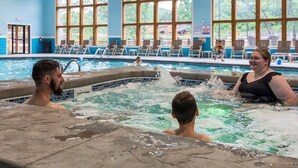 Ein Schwimmbecken mit gefliestem Rand, Liegestühlen und großen Fenstern.