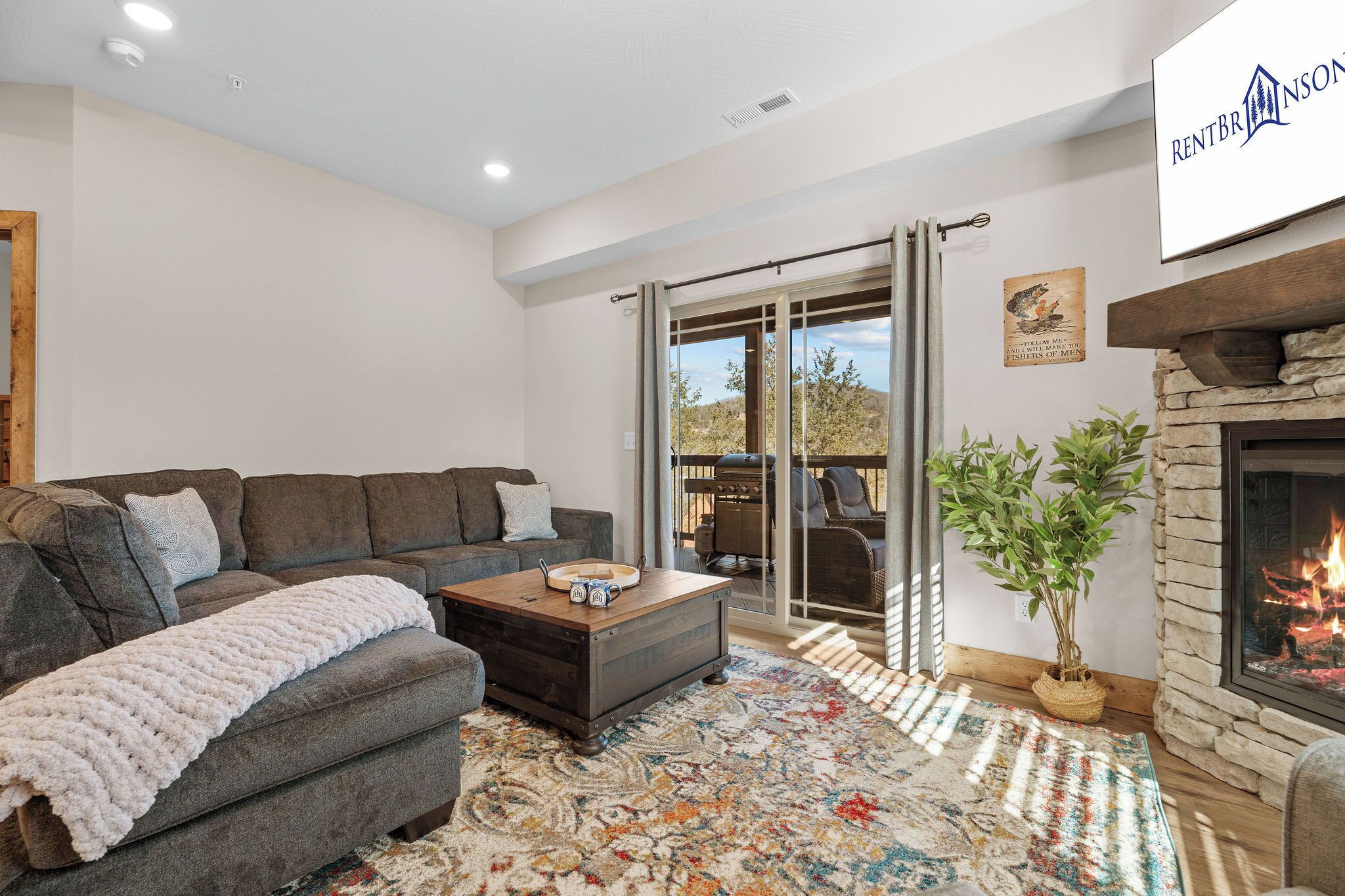 A living room with a sofa, coffee table, fireplace, and a view through a glass door.