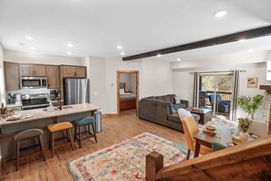 A modern kitchen with stainless steel appliances, a dining area with a wooden table and chairs, and a cozy living space with a sofa and a view of the outdoors. - Private Hot Tub at The Bobber Stop, Arcade, Community Pools Nearby & Free Attraction Tickets (Hollister)