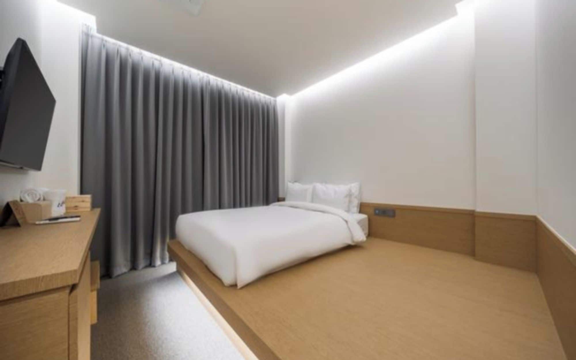 A hotel room with a bed, a desk, a television, and a window with curtains.