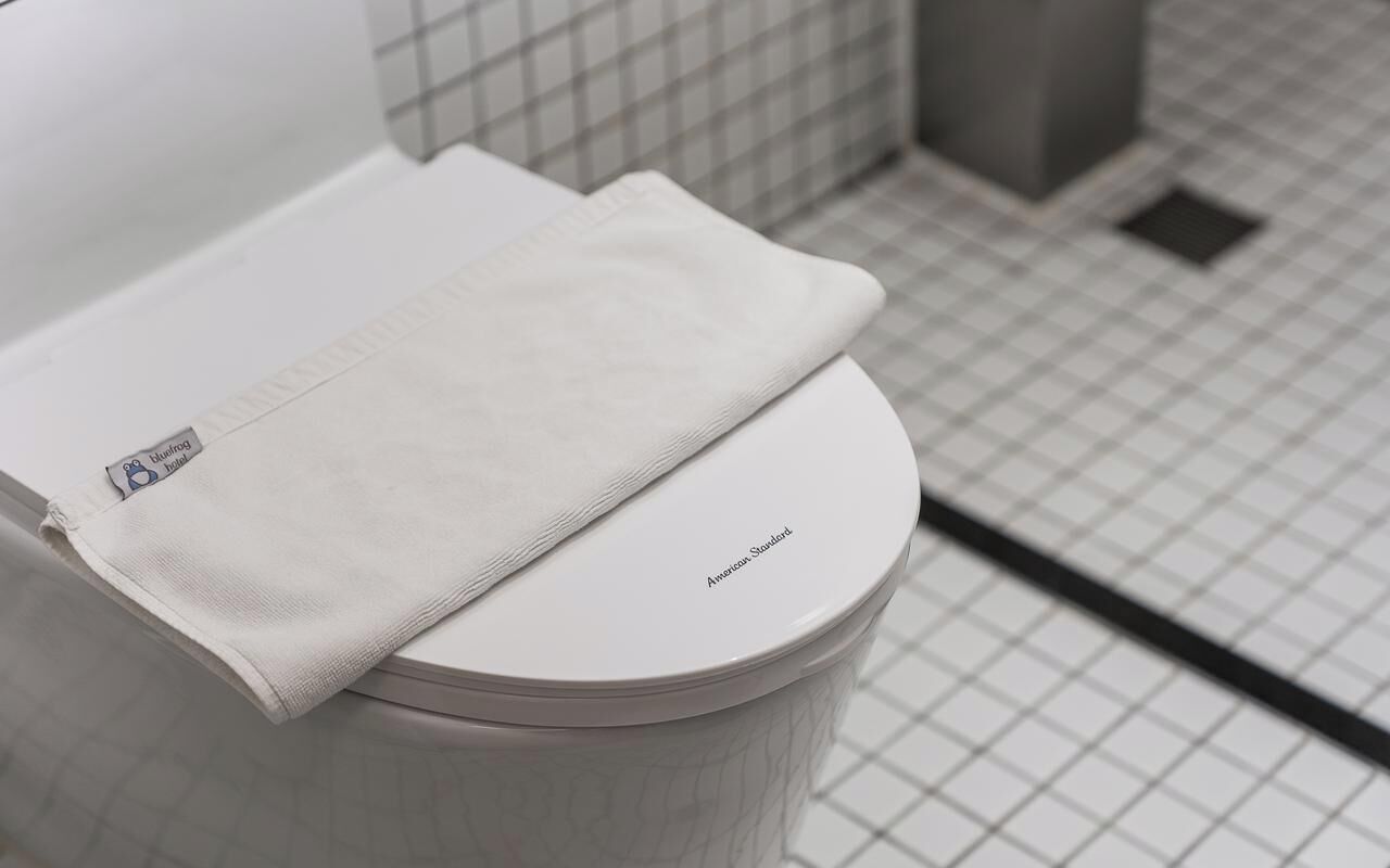 Des toilettes avec un abattant blanc et une serviette pliée posée dessus.