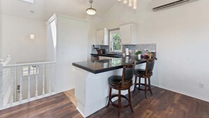 A kitchen with a central island, bar stools, pendant lighting, and a view of the outdoors. - Lakeview Home on Beaver with Balcony near DT Rogers (Rogers)