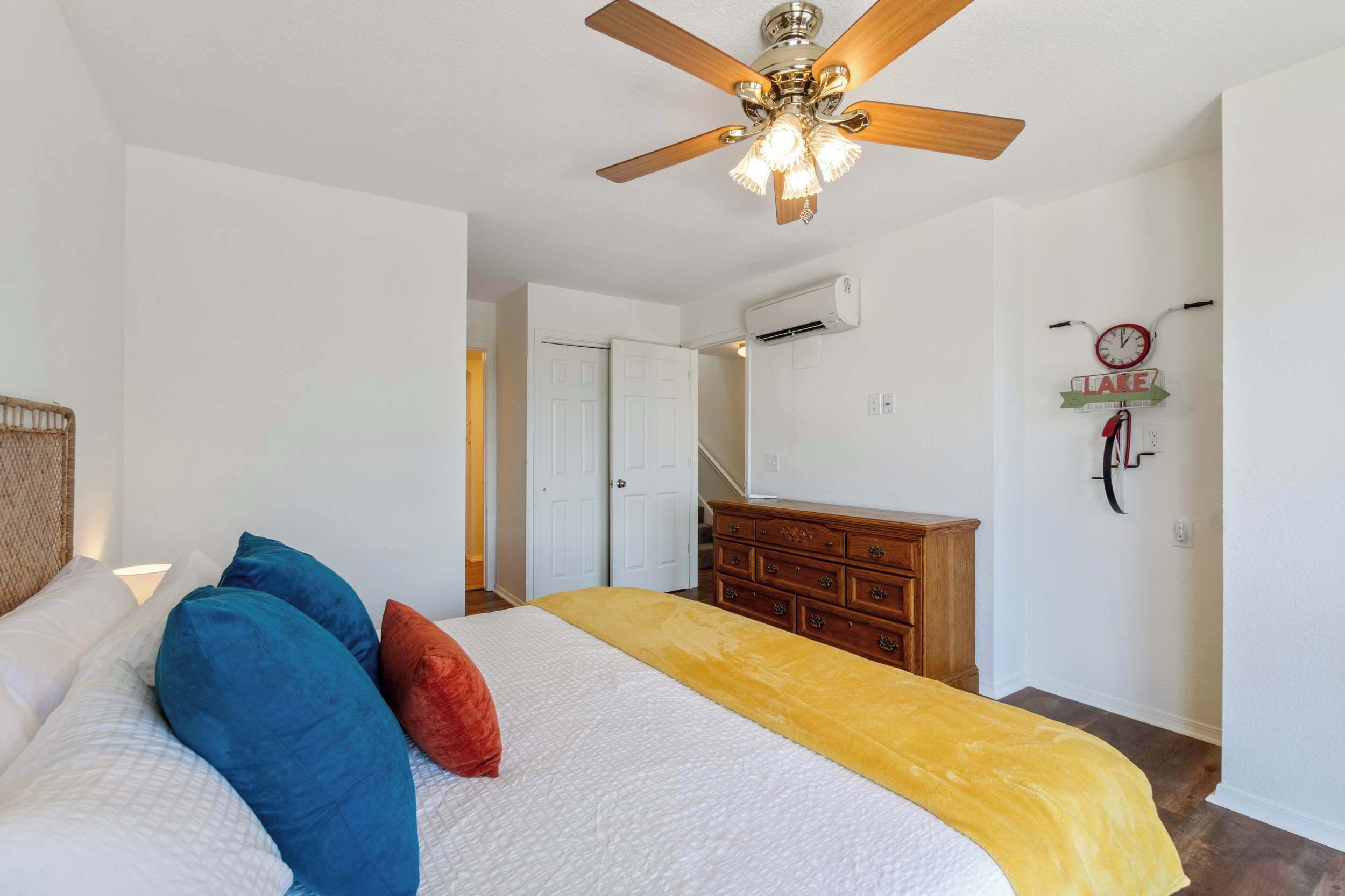 Une chambre à coucher avec un lit, un ventilateur de plafond, une commode et une horloge murale.