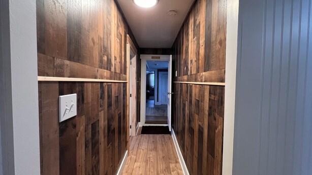 A narrow hallway with wooden panel walls and a light fixture on the ceiling. - Charming 5-bedroom house in Jackman / Moose River perfect for families, groups. (Moose River)