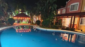 Ein Schwimmbecken mit einem Pavillon und Palmen.