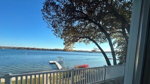 A lakeside view from a porch with a dock extending into the water. - Magician Lakefront - 7 bedrooms, 4.5 baths, screened in porch and coffee bar. (Dowagiac)
