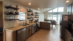 A modern kitchen with a central island, built-in appliances, and a dining area with a view. - Magician Lakefront - 7 bedrooms, 4.5 baths, screened in porch and coffee bar. (Dowagiac)