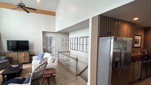 A spacious living area with a dining table, chairs, a sofa, a television, and a kitchen with a refrigerator. - Magician Lakefront - 7 bedrooms, 4.5 baths, screened in porch and coffee bar. (Dowagiac)