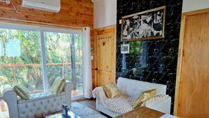 A cozy room with two white sofas, a glass coffee table, and a wooden ceiling.