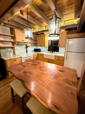 A kitchen with wooden cabinets, a stainless steel microwave, a white refrigerator, and a large wooden island with stools.