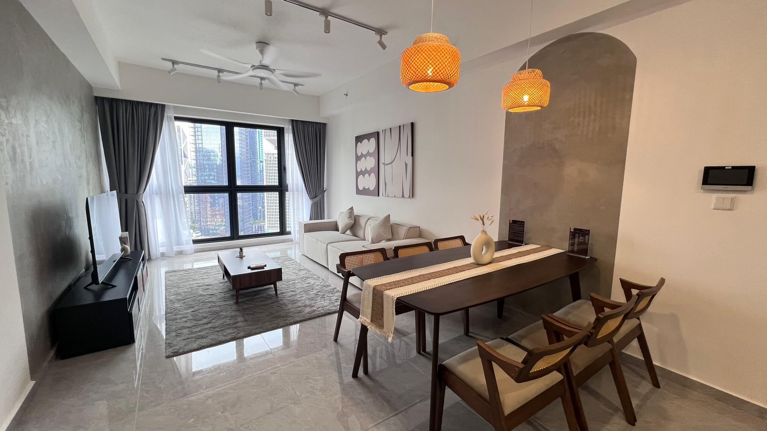 A modern living room with a dining area, large windows, and a view of high-rise buildings.