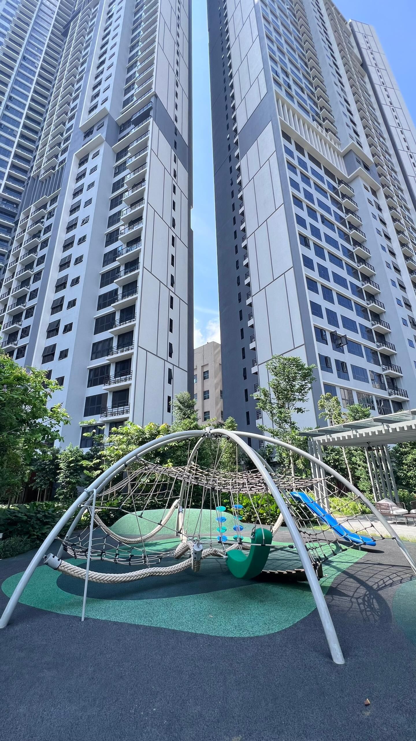 A playground with a rope swing and slide, surrounded by tall residential buildings.