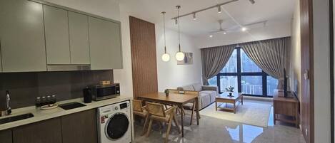 A modern kitchen with built-in appliances, a dining area with a wooden table and chairs, and a large window offering a city view.
