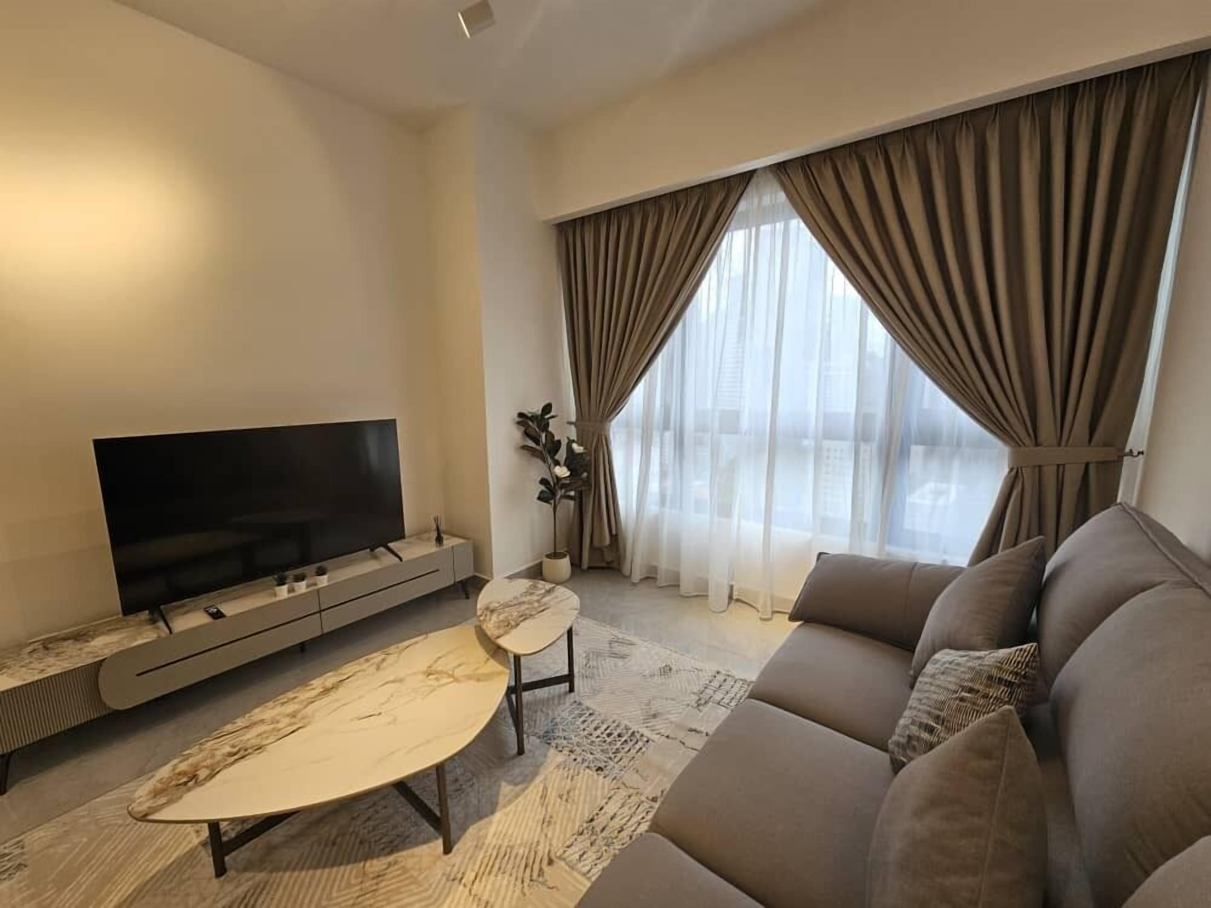 A modern living room with a flat-screen TV, a marble coffee table, a sofa, and a large window with curtains.