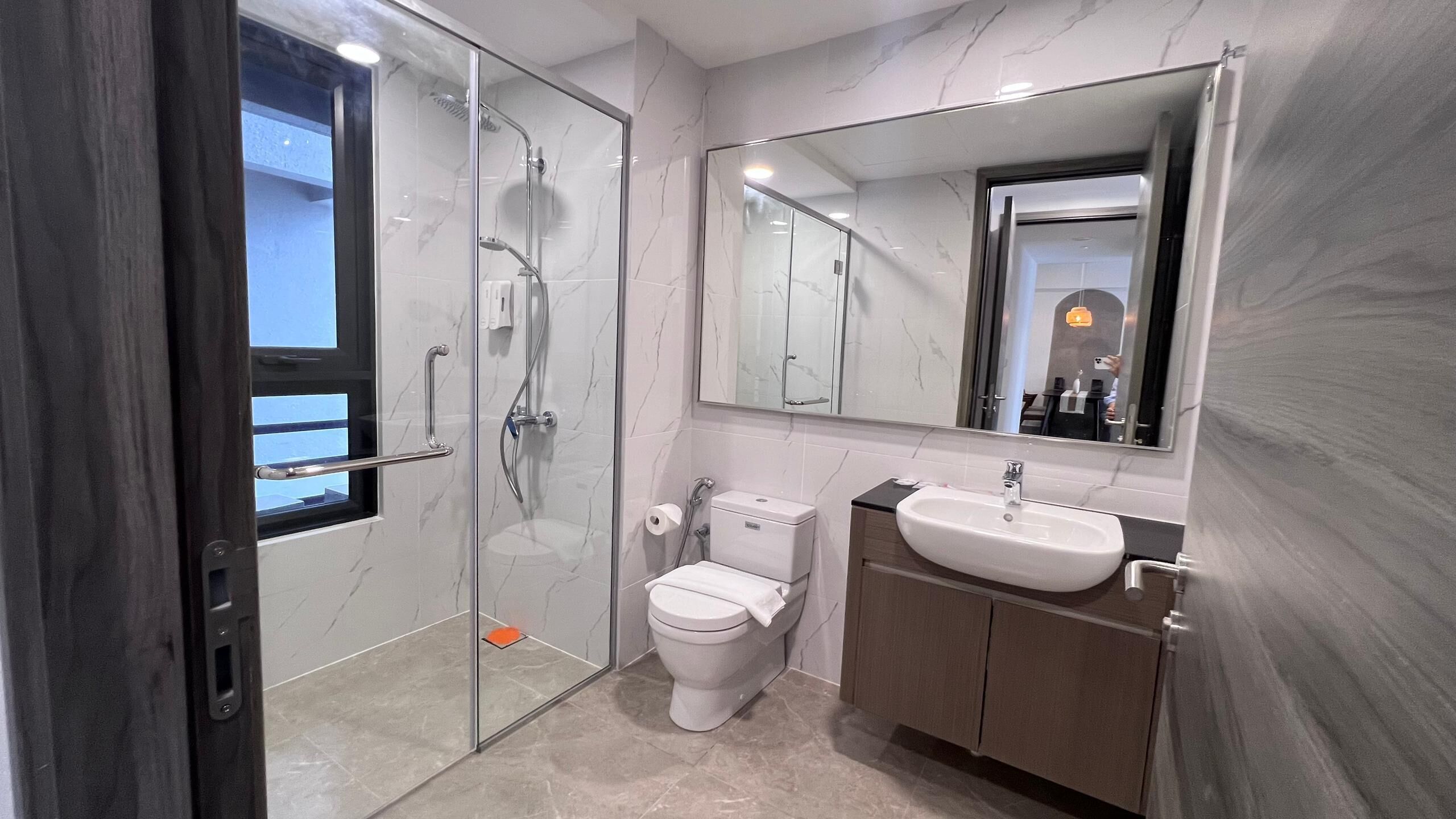 Une salle de bain moderne avec une douche à parois de verre, des toilettes, un lavabo et un grand miroir.