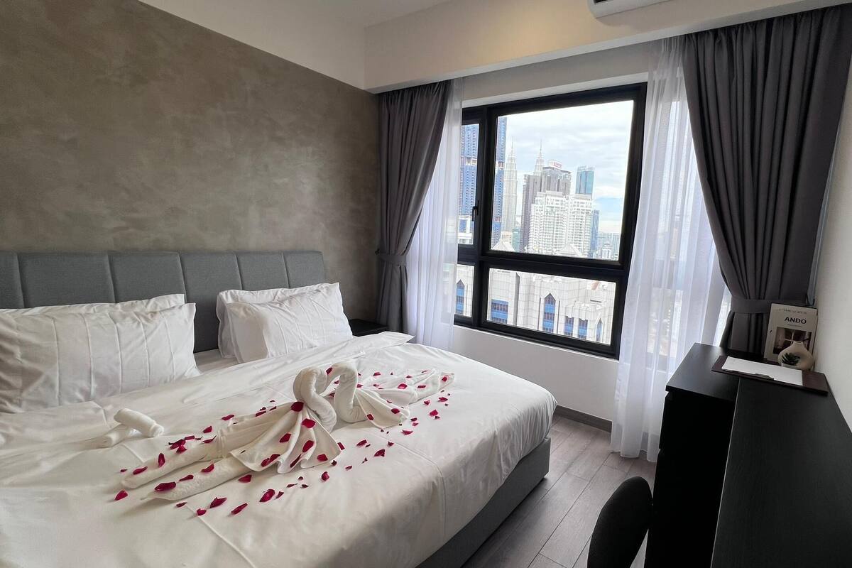 Habitación de hotel con una cama grande, un escritorio y una ventana con vistas a la ciudad.