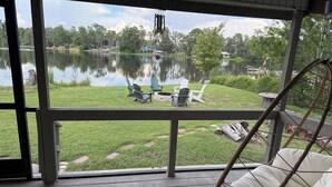 A porch with a view of a lake, outdoor furniture, and a hanging chair. - Lakefront Retreat Tampa, 7BR, Dock & Fun (Lutz)