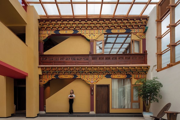A traditional building with a balcony, a potted plant, and a person standing in the doorway.