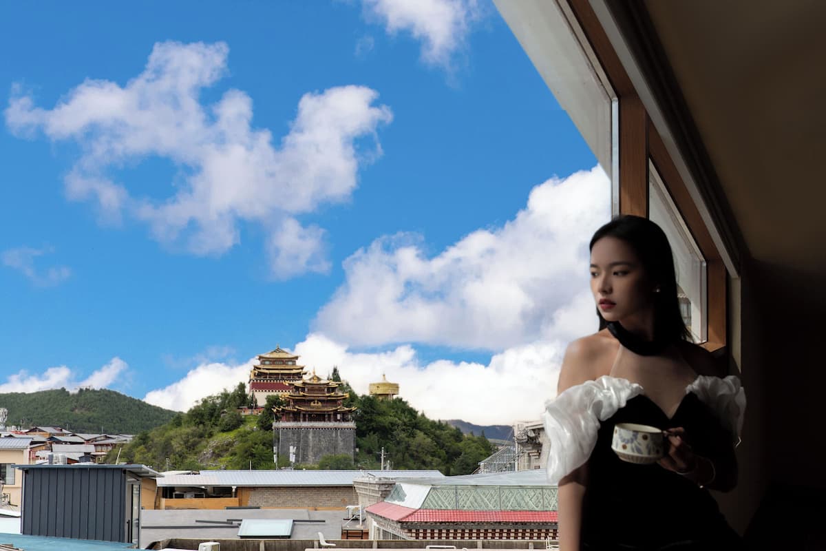Vista de um edifício tradicional com telhado em estilo pagoda, um edifício moderno com telhado vermelho, e um céu azul claro com nuvens.