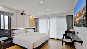 A modern hotel room with a large bed, a desk, and a projector. - WEN SI TE HOTEL  (Shanghai)