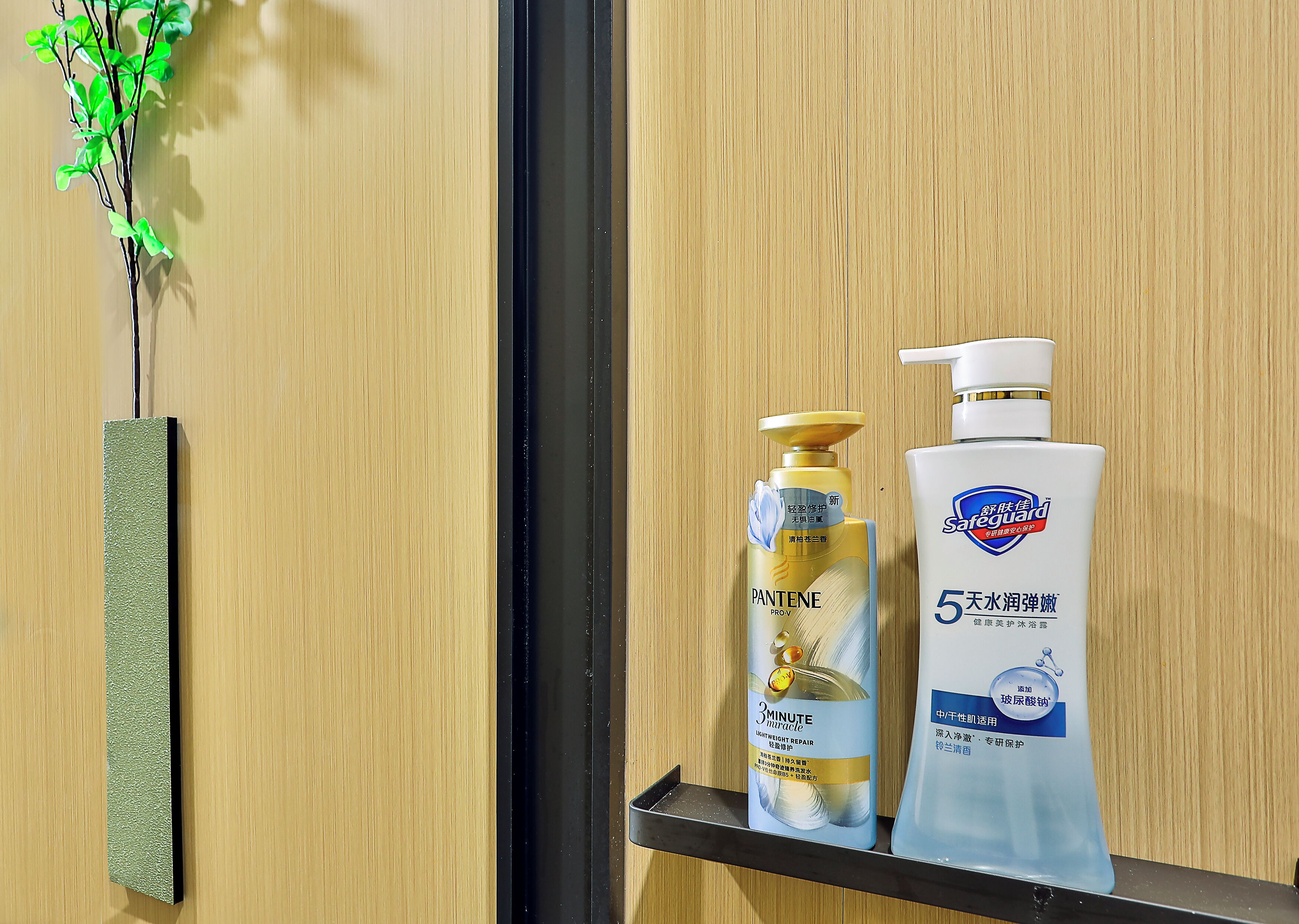 A shelf with two bottles of Pantene Pro-V and a bottle of Safeguard lotion against a wooden background.