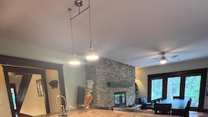 A kitchen with a large island, dark wood cabinets, a stone backsplash, and a view of the outdoors through large windows.
