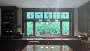 A kitchen with a large island, dark wood cabinets, and a window with a view of greenery.