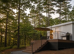 A cabin with a staircase leading to a deck, surrounded by a forest.