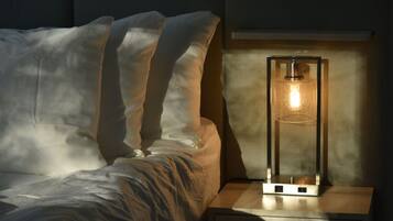 A bed with white linens and a nightstand with a lamp.