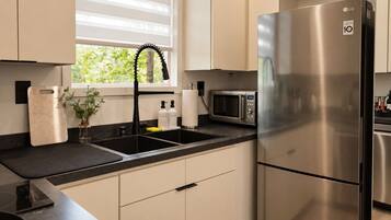 A modern kitchen with a stainless steel refrigerator, a microwave, and a sink with a faucet.